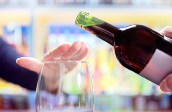Womans hand rejecting more alcohol from wine bottle in bar